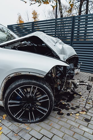 A close-up of a car interior after a frontal collision with a lamppost, showing deployed airbags, a shattered windshield, and a crumpled dashboard.