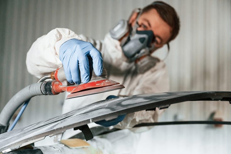 Skilled repairman using a polishing tool to restore the shine of a car's paintwork.