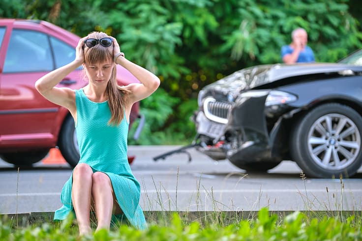 Stressed driver experiencing shock and anxiety after a collision, emphasizing the need for comprehensive car insurance.