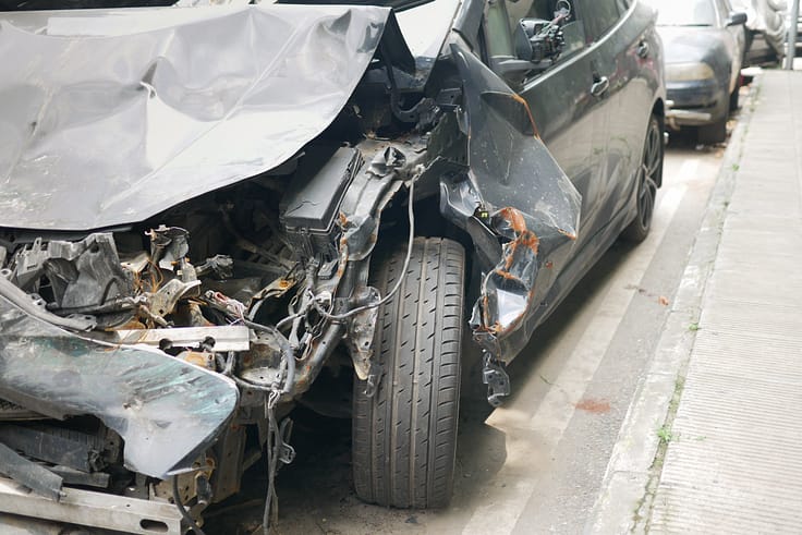 A black car with significant front-end damage from a road accident in Atlanta.