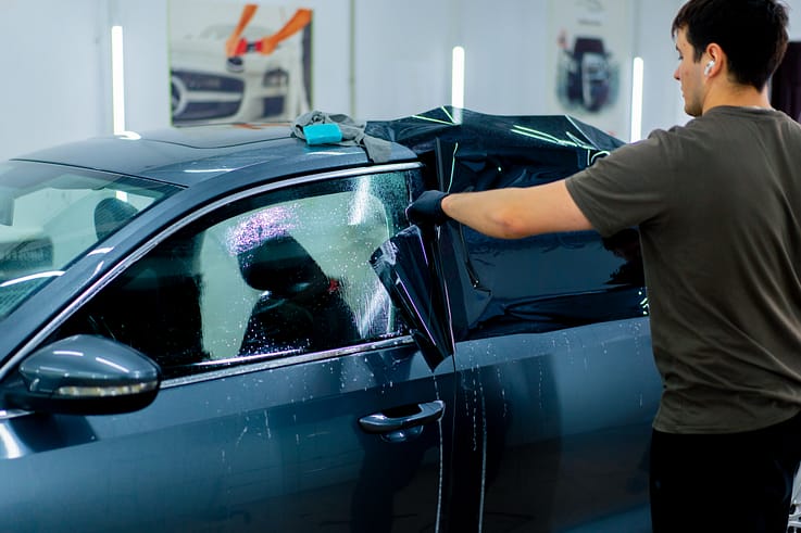 A car mechanic working on a car at a detailing station.