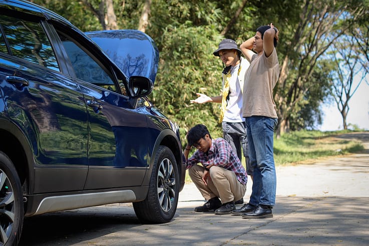 A group of friends trying to jump-start a dead battery on a car.