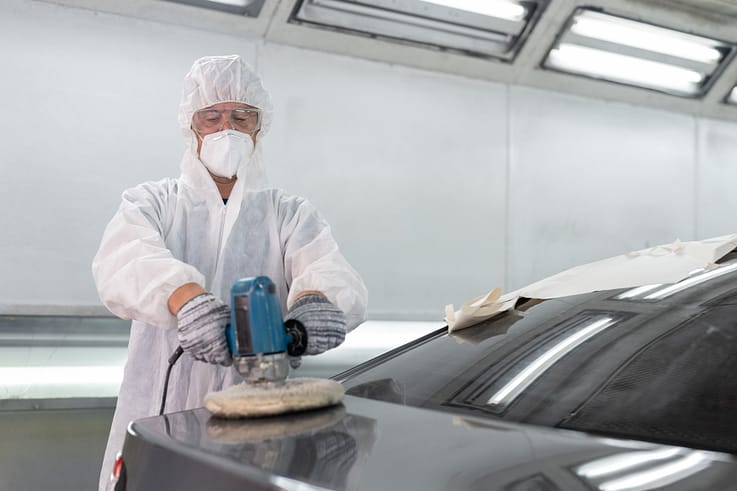 Detail-oriented professional using specialized equipment to buff and polish a newly painted car body to perfection.