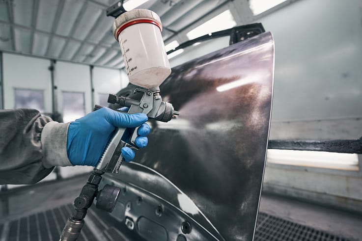 Skilled repairman using a polishing tool to restore the shine of a car's paintwork.