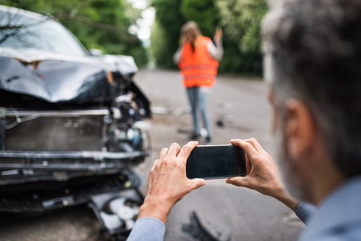 Person documenting damage to a car after a collision for insurance purposes.v