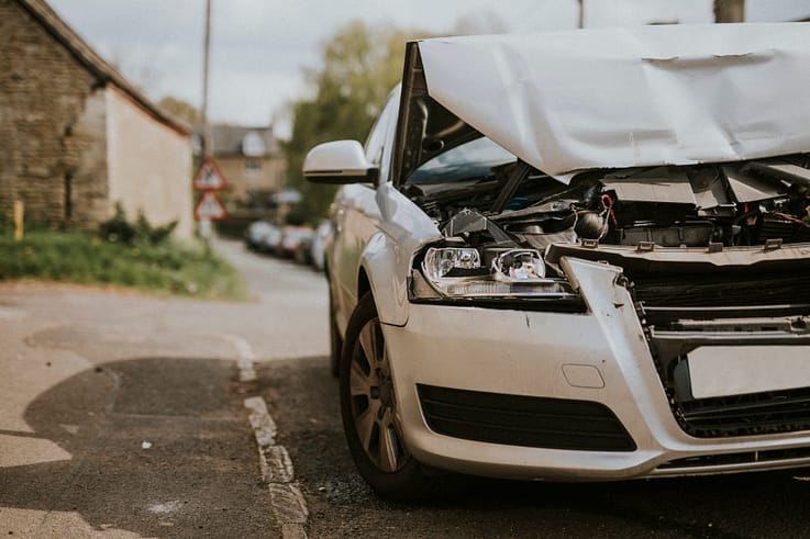 Abandoned car with deployed airbags and shattered windshield after a serious crash.