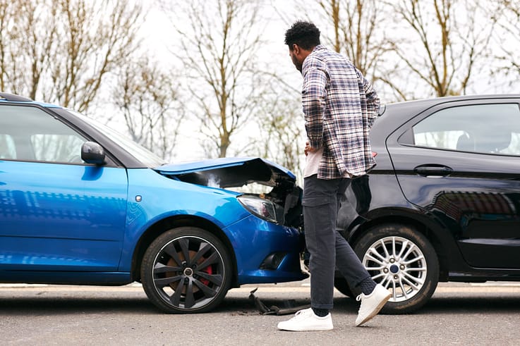 Distressed driver examining his vehicle after a collision.