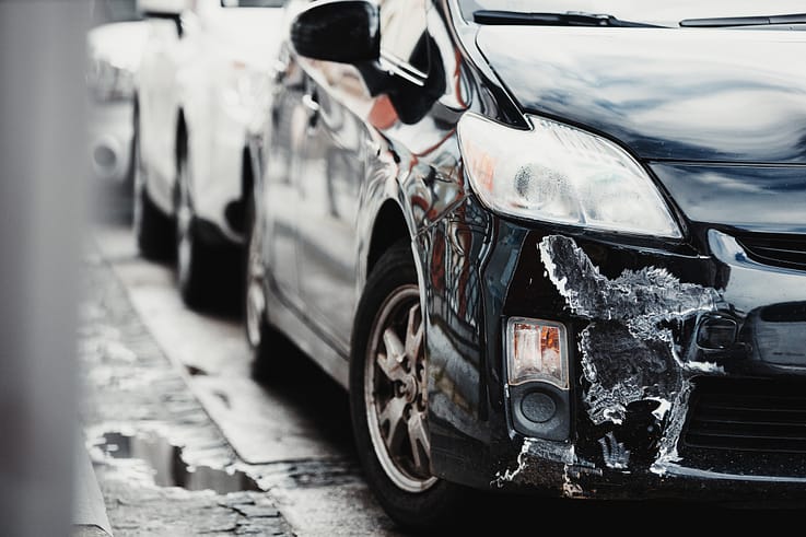 Close-up of a damaged car bumper and fender with deep scratches and dents after a collision in Atlanta.