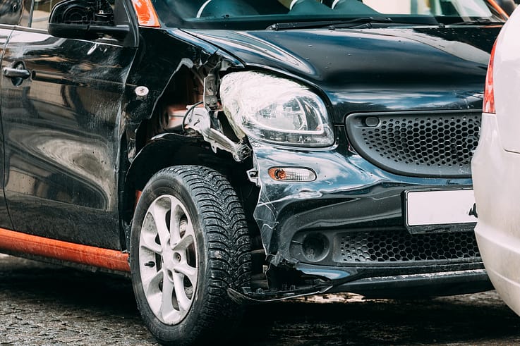 A close-up of a car's damaged bumper and fender after a collision in Atlanta, showing deep scratches and dents in the paintwork.