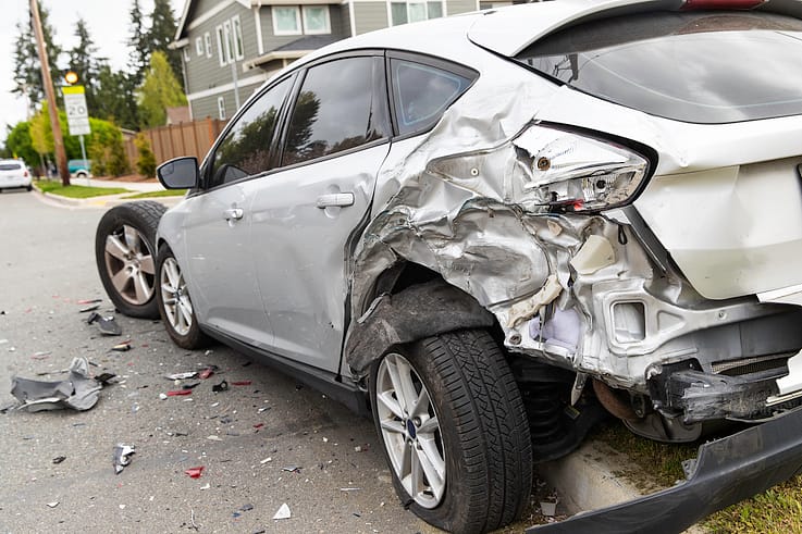 A silver car with significant rear-end damage from a collision in Atlanta.