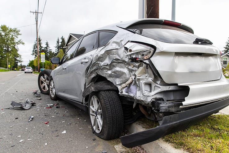 A photo of a car crash scene from behind, showing the mangled wreckage of two vehicles.