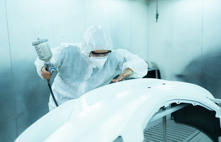 A skilled painter meticulously checking for any flaws in a freshly painted car, ensuring a flawless finish.